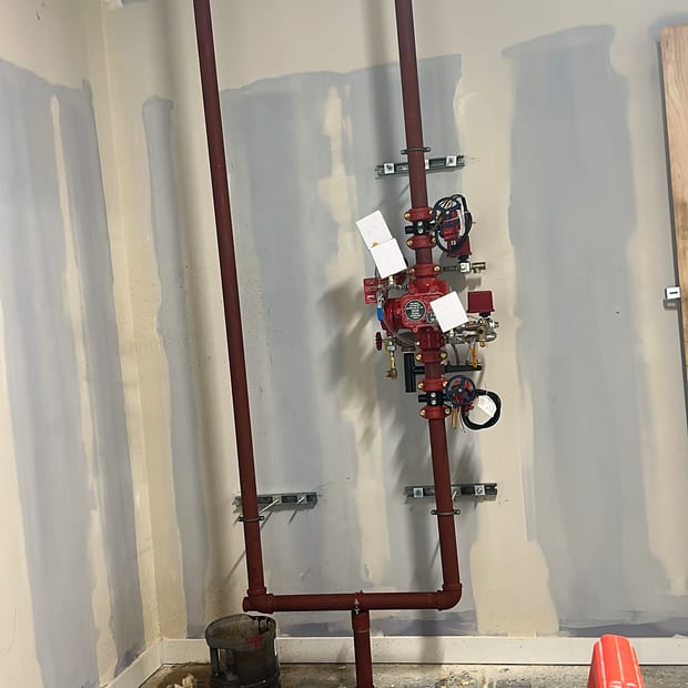 Sprinkler alarm valve set and riser on a wall in a room under fit-out