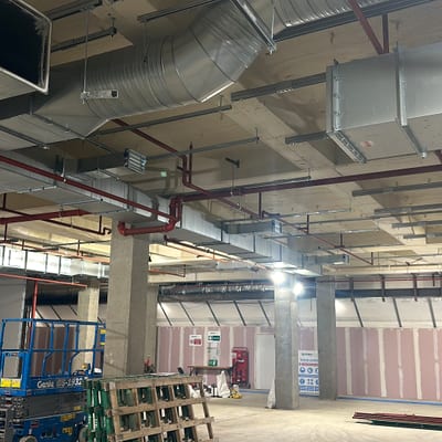 Red sprinkler mains running under the soffit of a commercial unit during fit-out