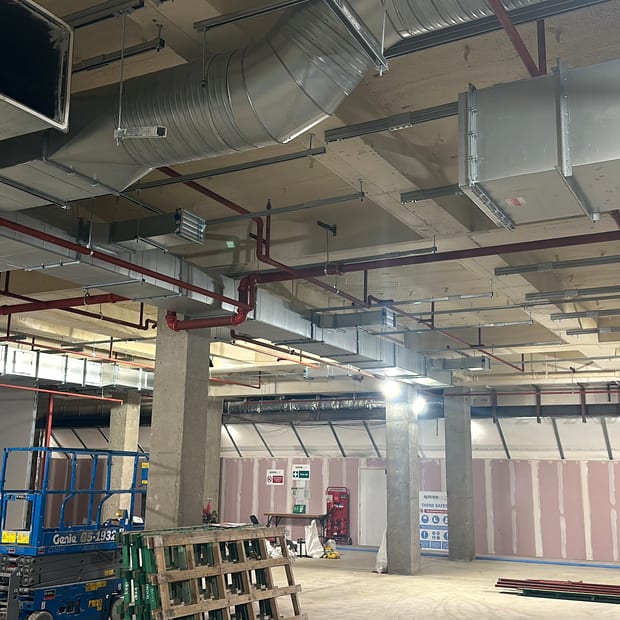 Red sprinkler mains running under the soffit of a commercial unit during fit-out