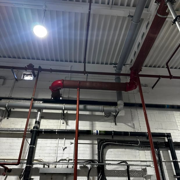 High level sprinkler main under an exposed metal deck