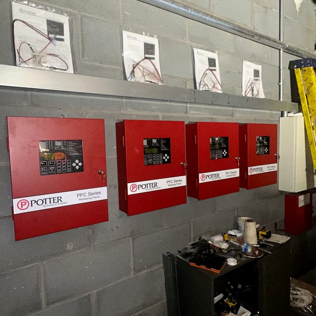 Four POTTER control panels and an alarm bell on a plant room wall
