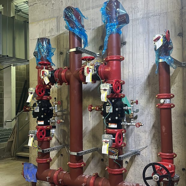 Three sprinkler control valve sets installed on a plant room wall
