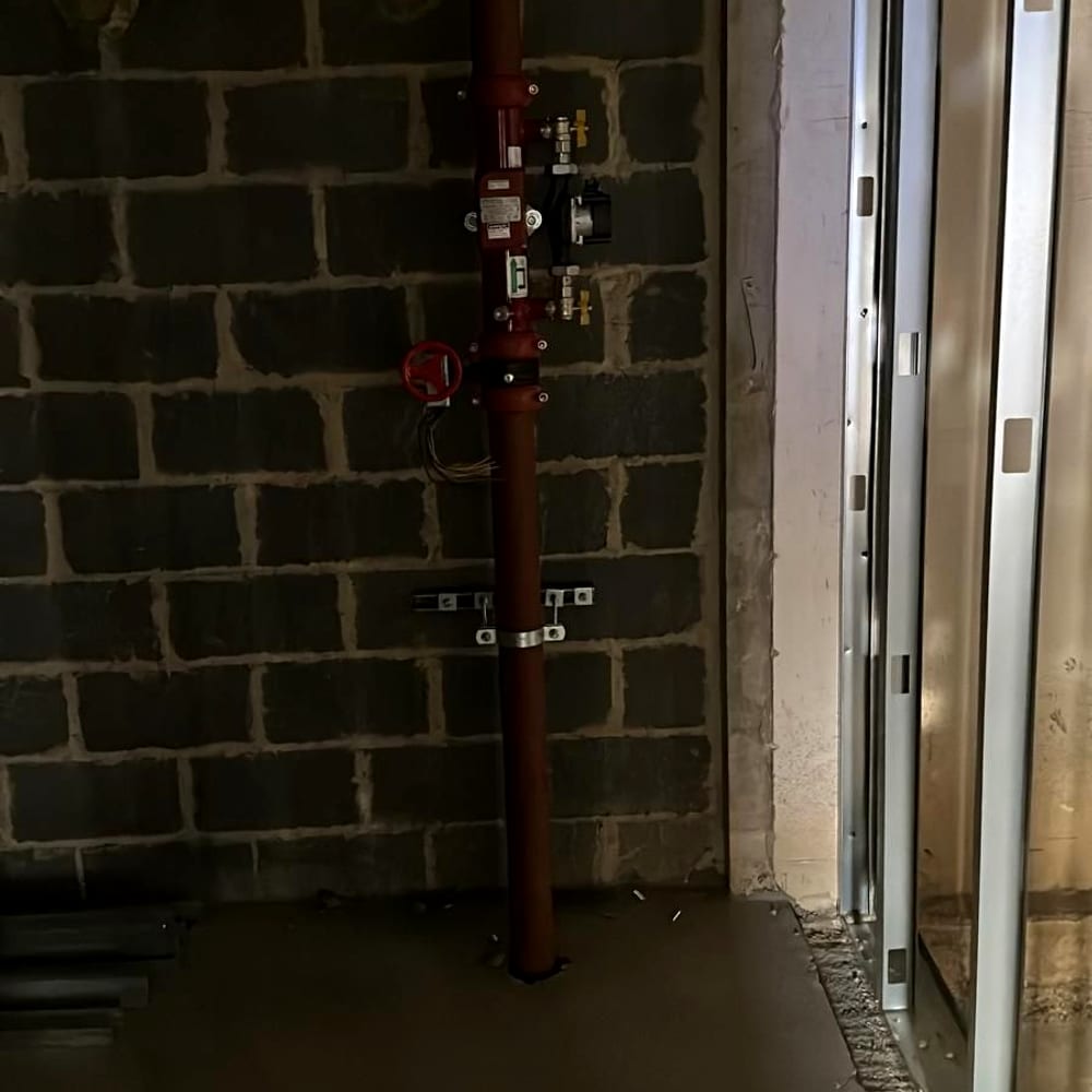 A sprinkler zone control valve on a red riser, the kind of equipment sprinkler servicing for housing associations covers