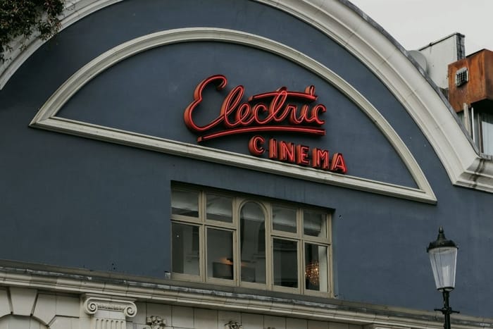A neon cinema sign on a painted period facade