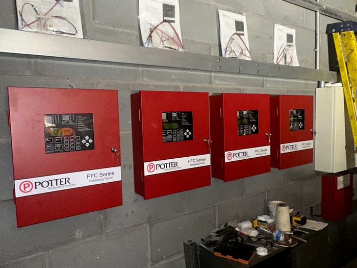 Sprinkler monitoring panels and an alarm bell in a plant room