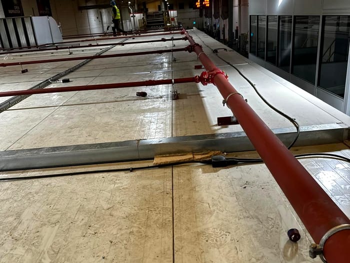 Sprinkler main being installed across a warehouse roof