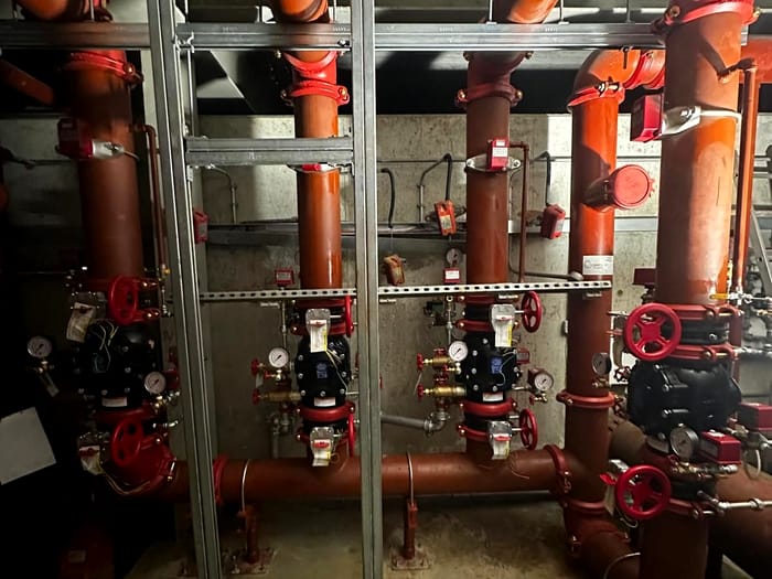 Three sprinkler control valve sets on a plant room wall